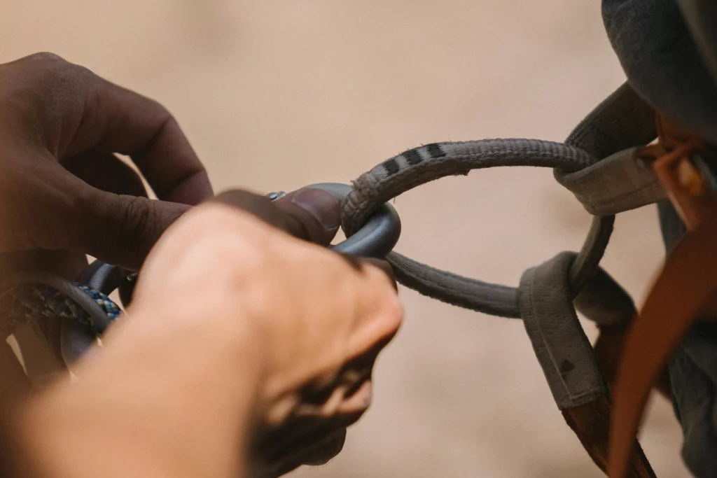 Gros plan sur des mains manipulant un mousqueton et une corde de sécurité pour une intervention en hauteur.