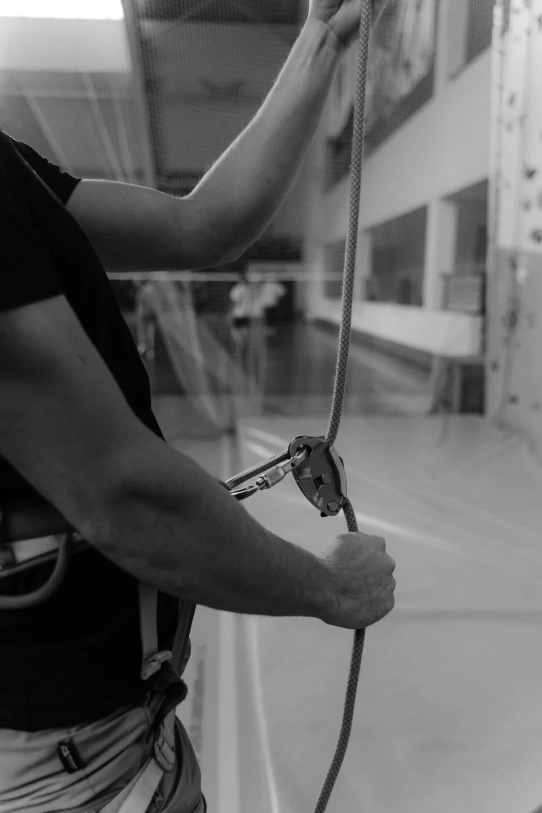Gros plan sur une personne équipée d’un harnais manipulant une corde et un descendeur pour une intervention sur cordes.